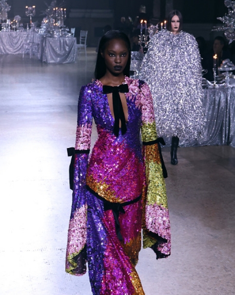 Model walking down runway with multi-color dress